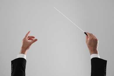 Photo of Professional conductor with baton on light grey background, closeup