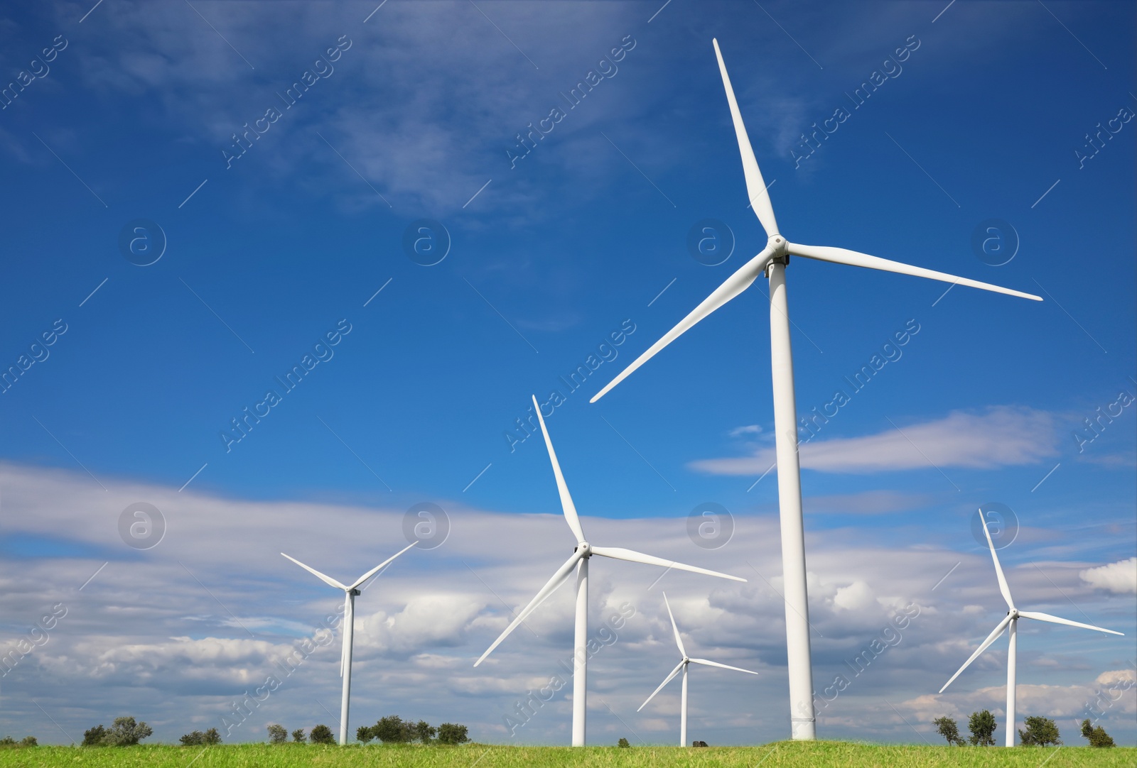 Image of Alternative energy source. Wind turbines in field under blue sky