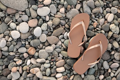 Photo of Stylish beige flip flops on pebble seashore, top view. Space for text