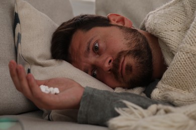 Photo of Depressed man with antidepressants lying on bed