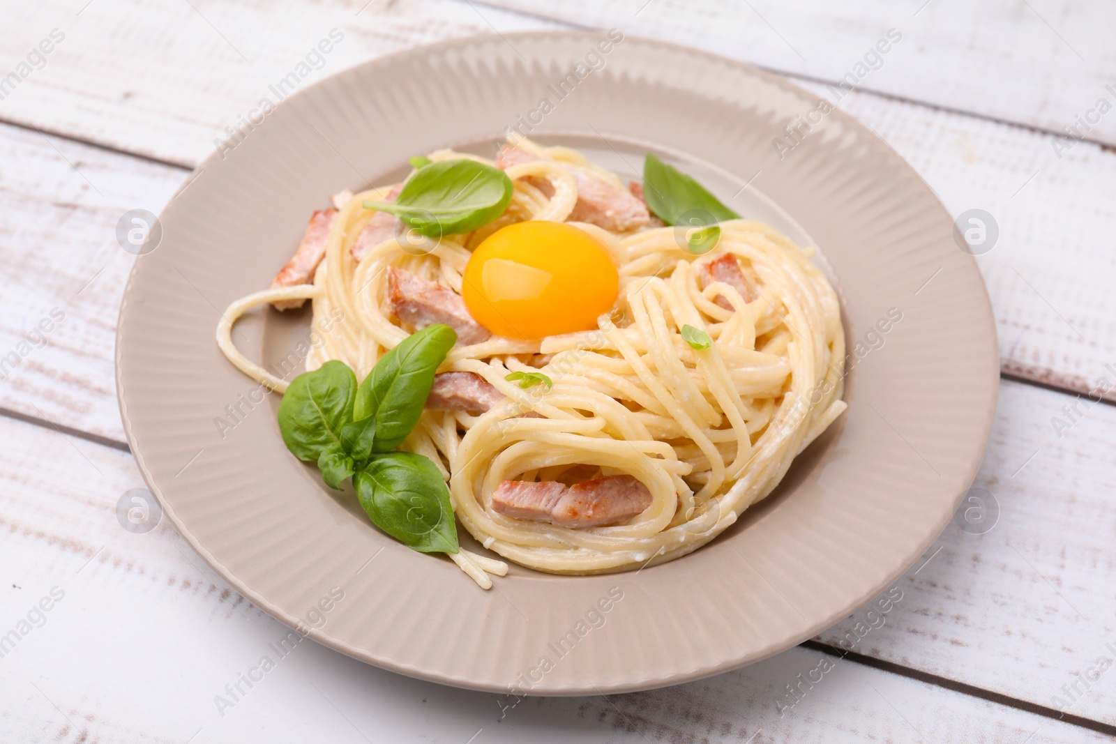 Photo of Delicious pasta Carbonara with egg yolk on white wooden table, closeup