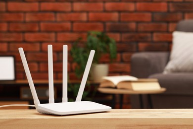 Photo of New white Wi-Fi router on wooden table indoors. Space for text