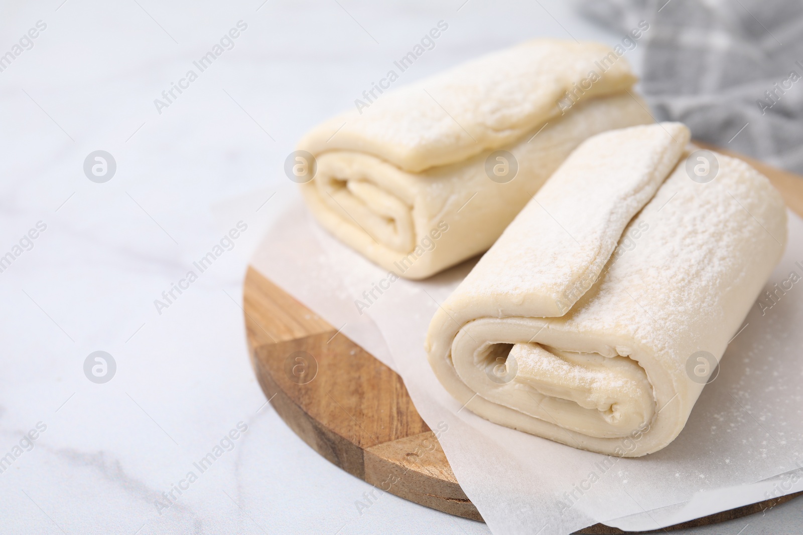 Photo of Raw puff pastry dough on white marble table, closeup. Space for text