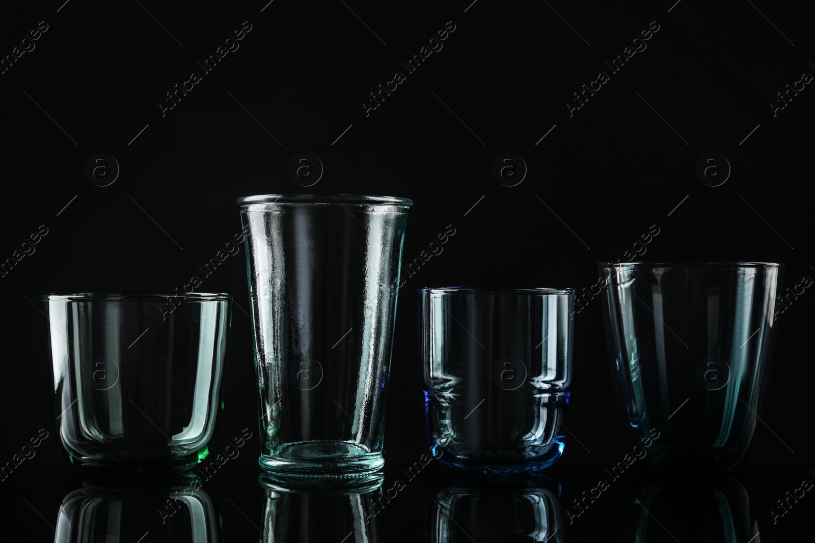 Photo of Set of different colorful empty glasses on black background