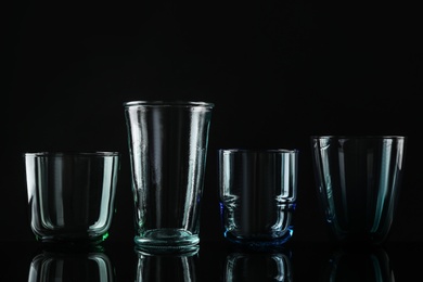 Photo of Set of different colorful empty glasses on black background