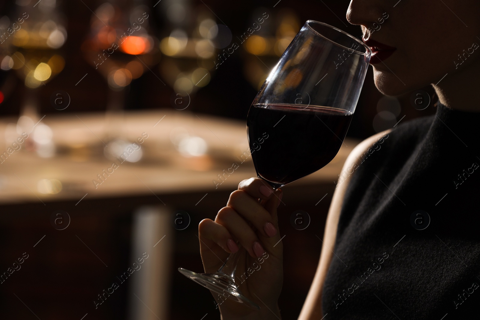 Photo of Woman with glass of red wine against blurred background, closeup. Space for text