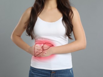 Young woman suffering from liver pain on grey background, closeup