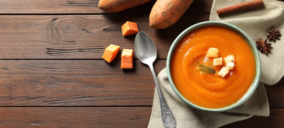 Tasty sweet potato soup on wooden table, flat lay with space for text. Banner design