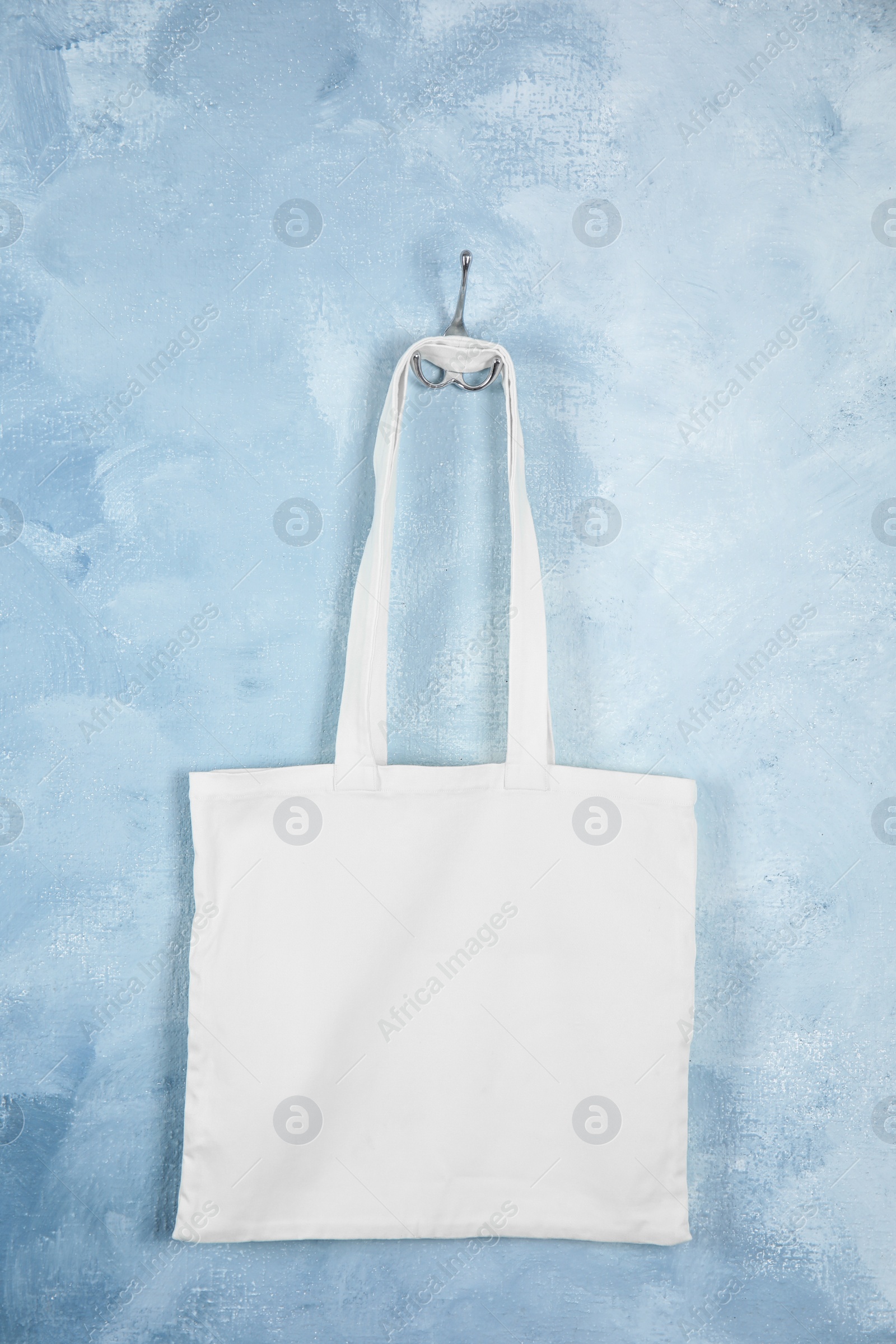 Photo of Tote bag hanging on color wall. Mock up for design