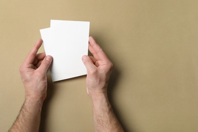 Photo of Man holding flyers on light brown background, top view. Mockup for design