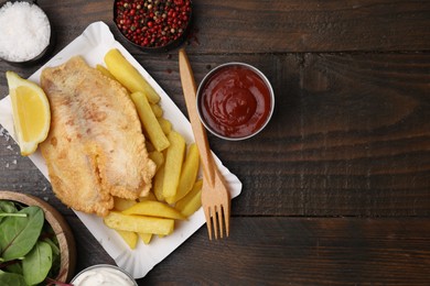 Photo of Delicious fish and chips served on wooden table, flat lay. Space for text