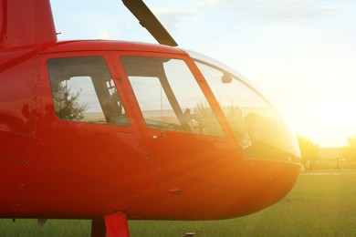 Modern red helicopter on green grass outdoors