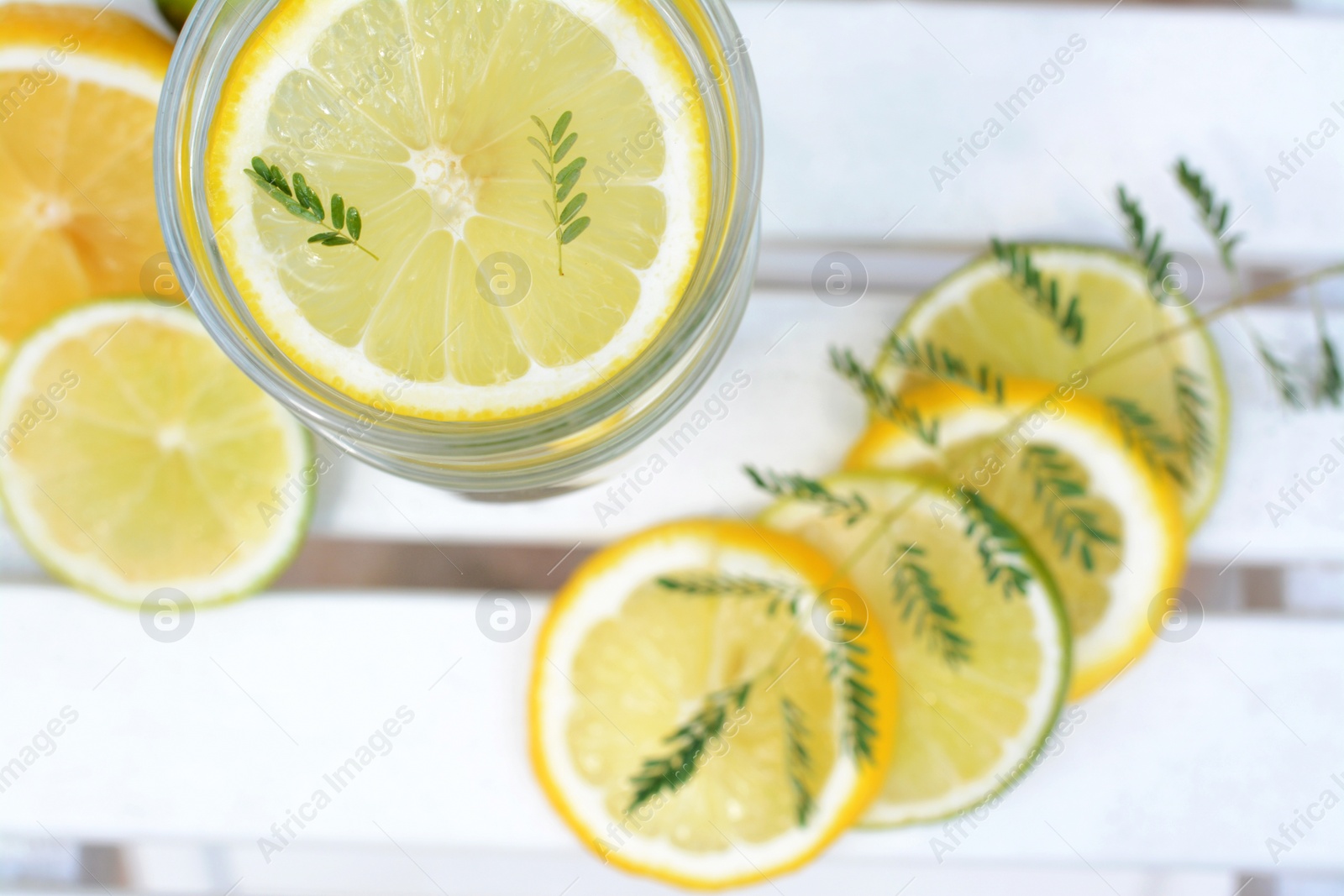 Photo of Delicious refreshing lemonade and pieces of citrus on white wooden table outdoors, flat lay