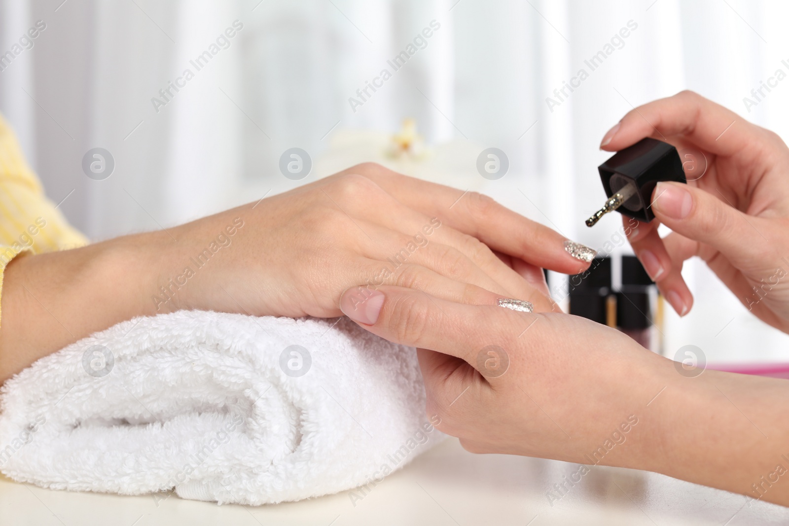 Photo of Manicurist painting client's nails with polish in salon, closeup