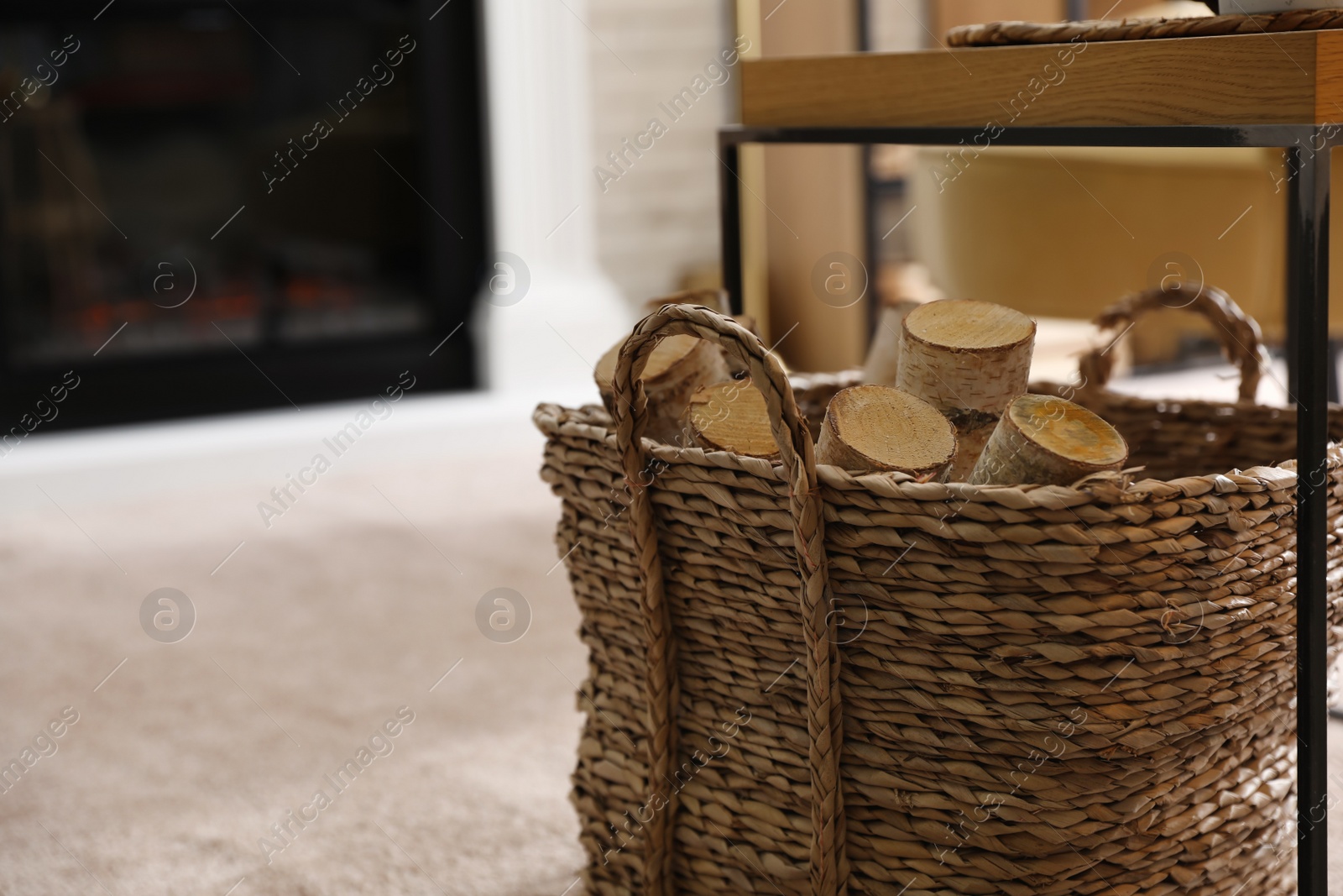 Photo of Firewood in wicker basket in room, closeup view