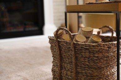 Firewood in wicker basket in room, closeup view