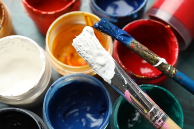 Jars with color paints and brushes on table, closeup