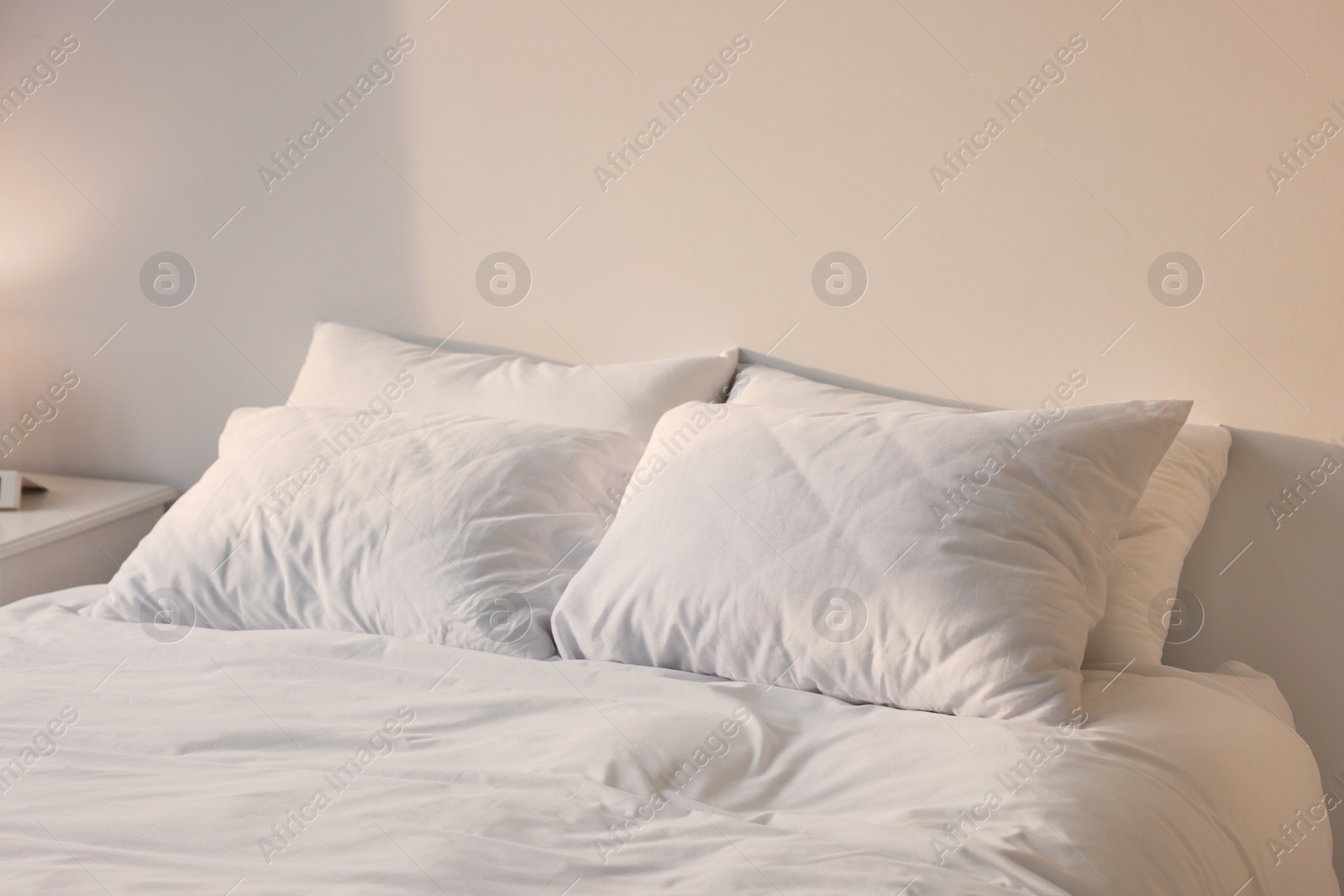 Photo of White soft pillows on bed in room