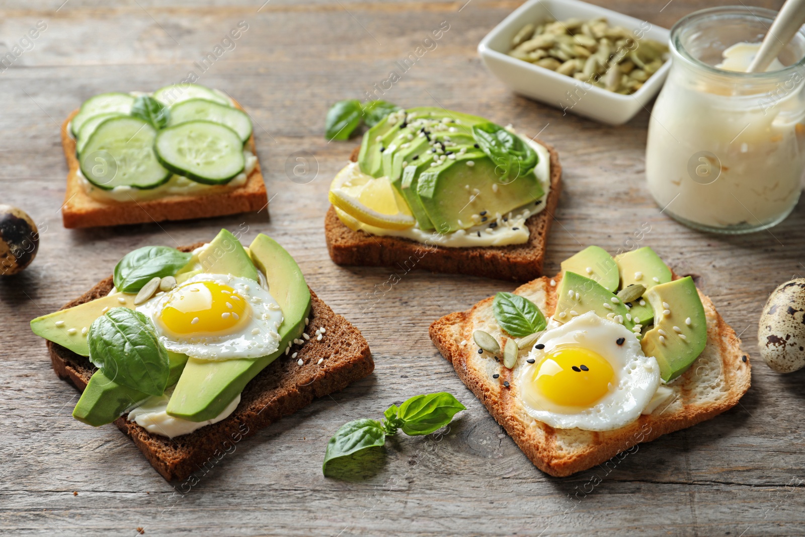 Photo of Toast bread with fried eggs, avocado and cucumber slices on wooden table