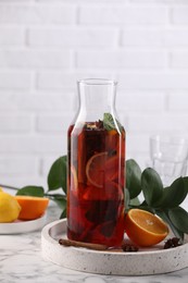 Photo of Delicious punch drink in bottle and ingredients on white marble table
