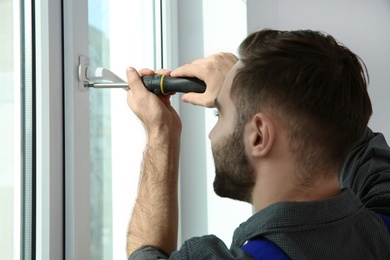 Professional construction worker installing window in apartment