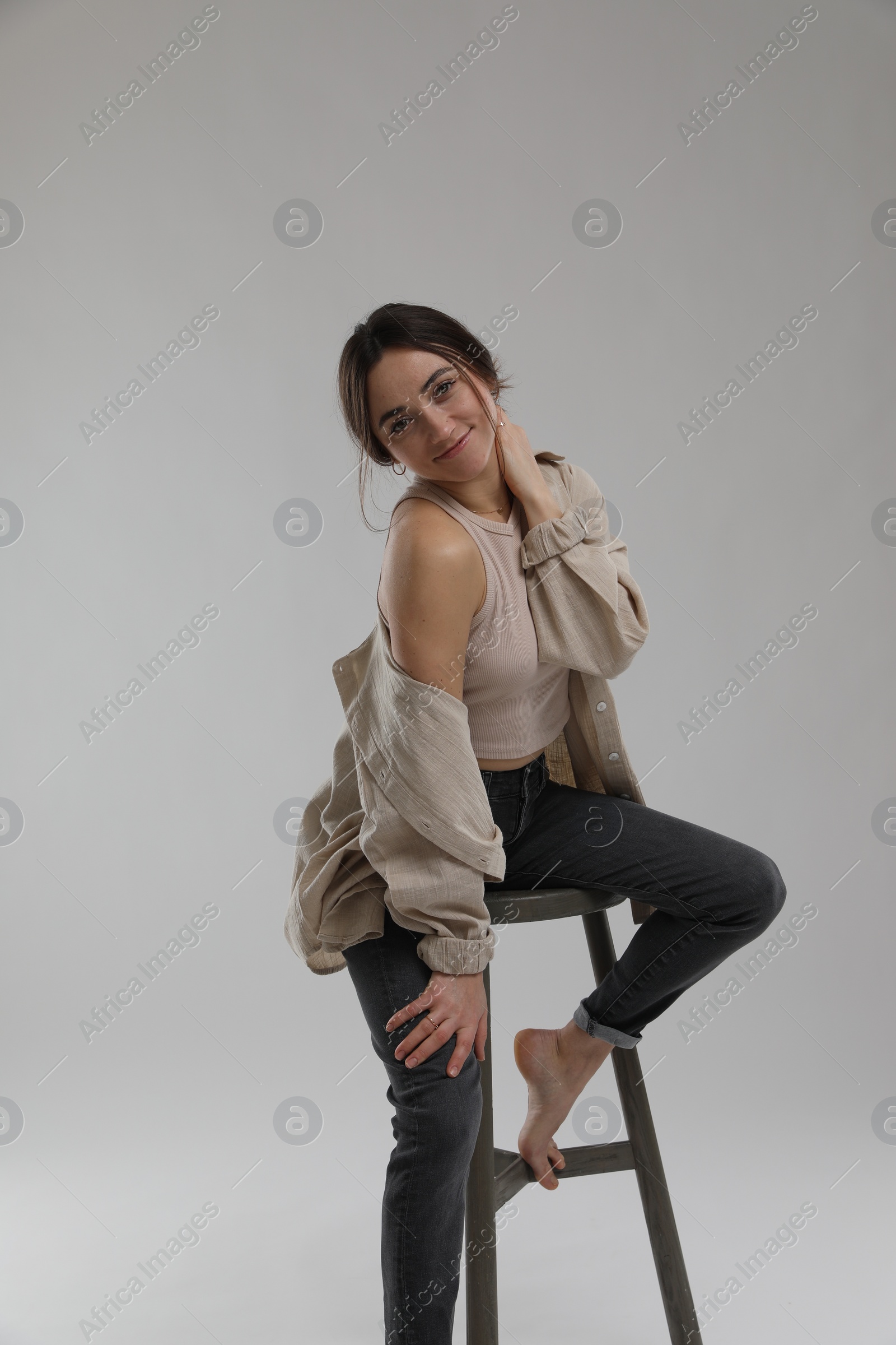 Photo of Portrait of beautiful woman sitting on chair against light grey background