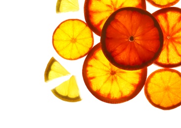 Illuminated slices of citrus fruits on white background, top view