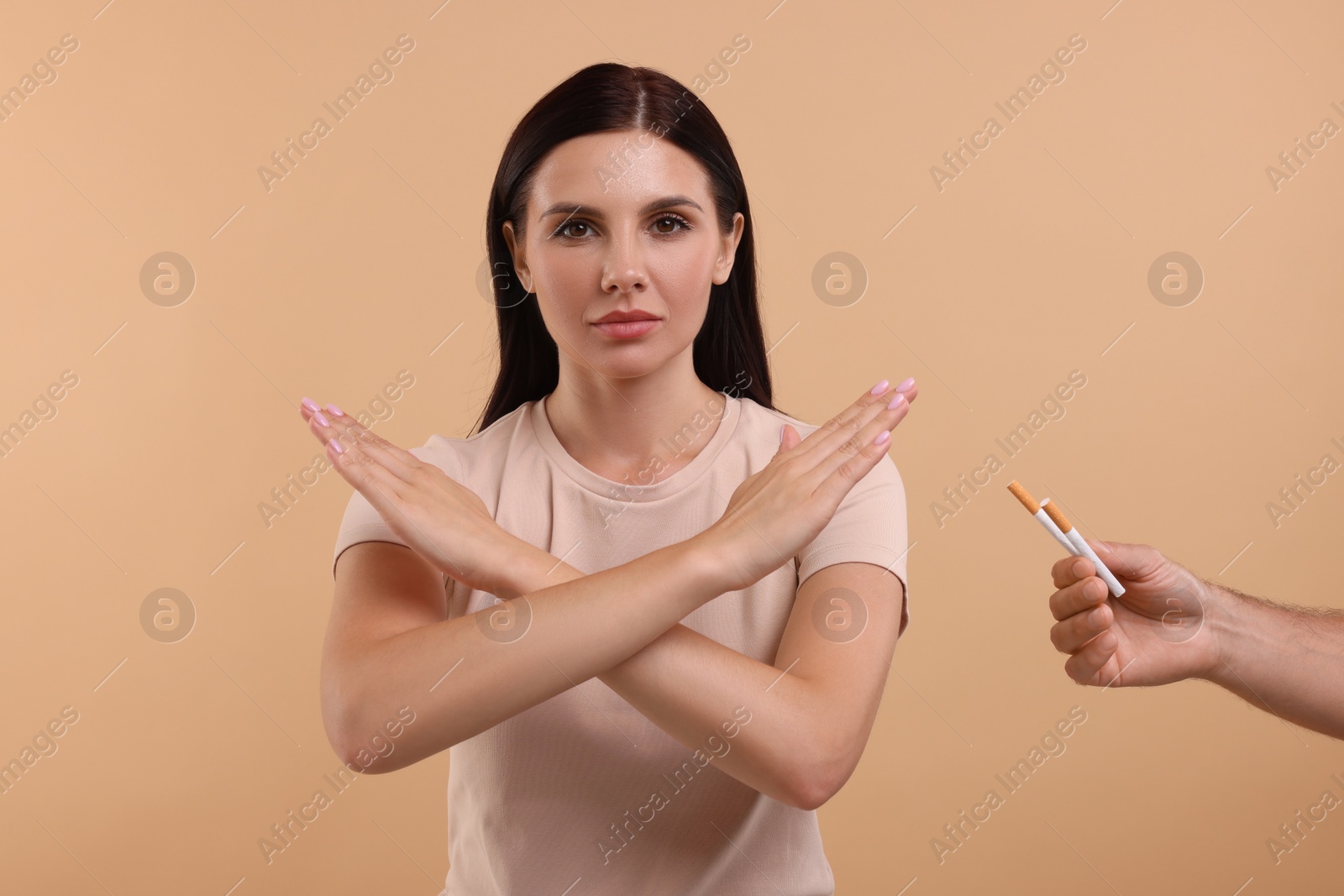 Photo of Stop smoking concept. Young woman refusing cigarettes on light brown background