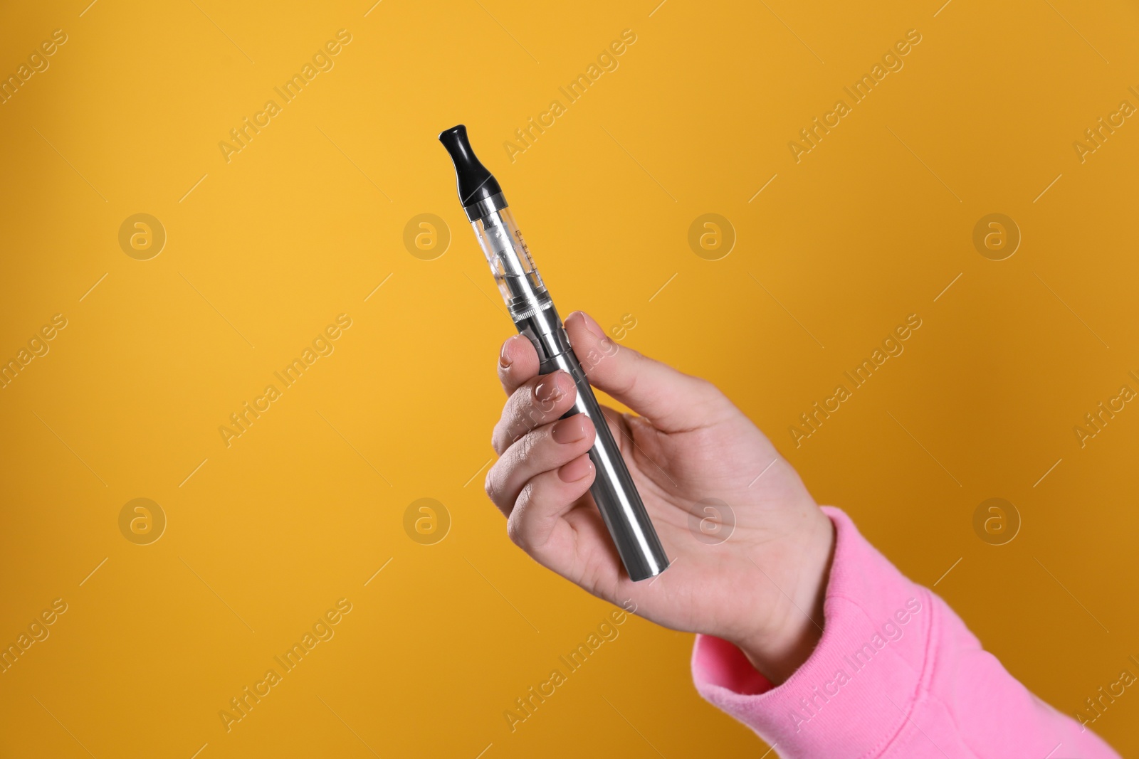 Photo of Woman holding electronic cigarette on orange background, closeup