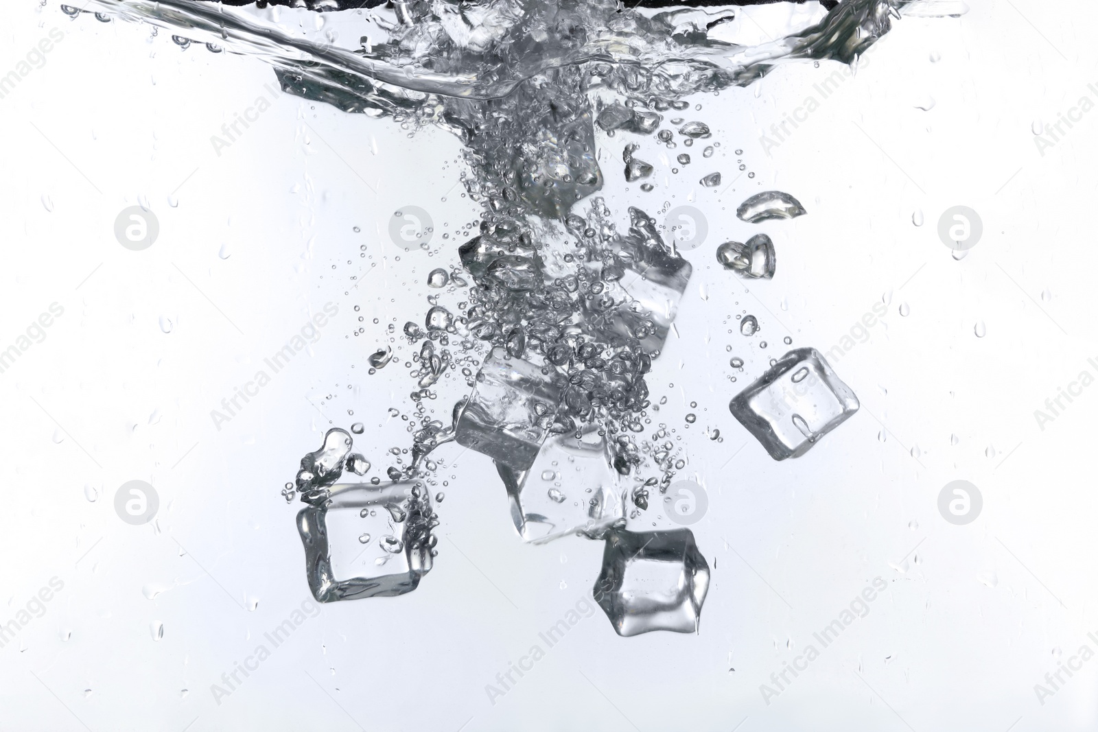 Photo of Ice cubes falling into water against white background