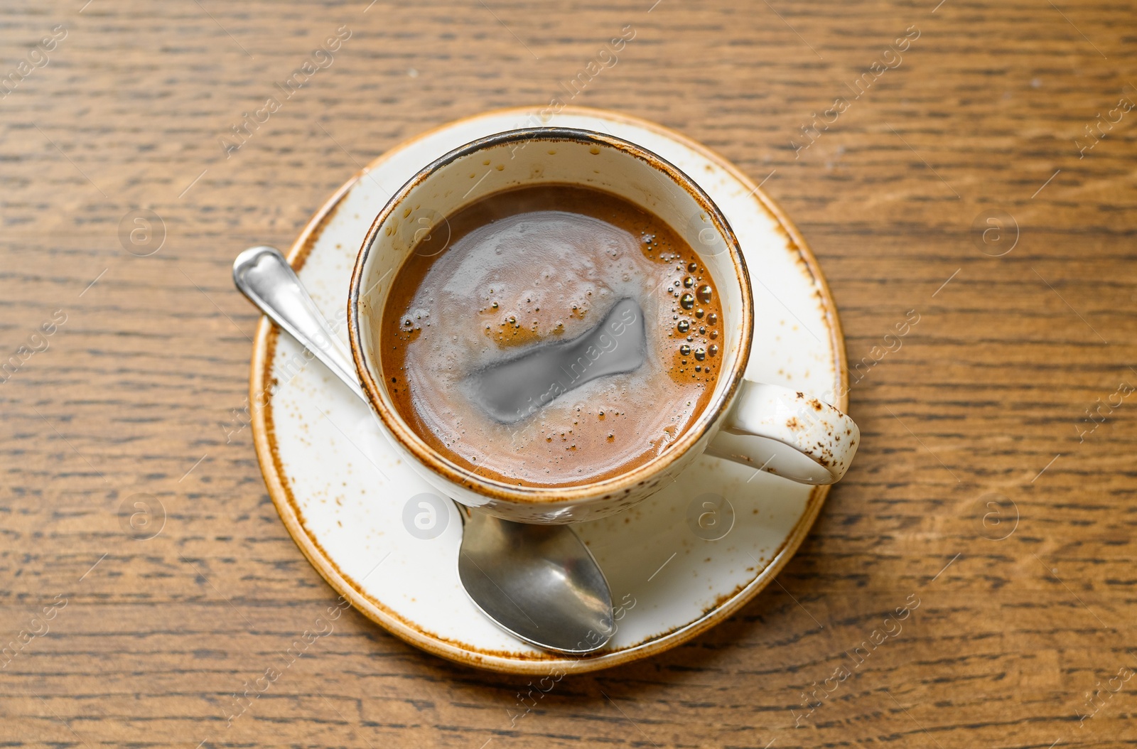 Photo of Cup of aromatic coffee on wooden table, top view