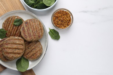 Tasty grilled vegan cutlets served on white marble table, flat lay. Space for text