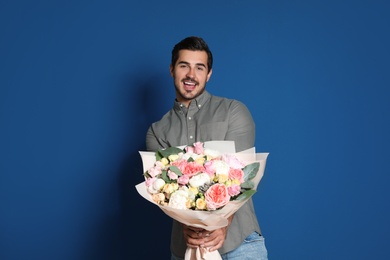 Photo of Young handsome man with beautiful flower bouquet on blue background