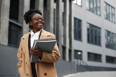 Photo of Happy woman with folders outdoors, space for text. Lawyer, businesswoman, accountant or manager