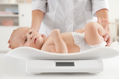 Photo of Doctor weighting baby on scales in light room