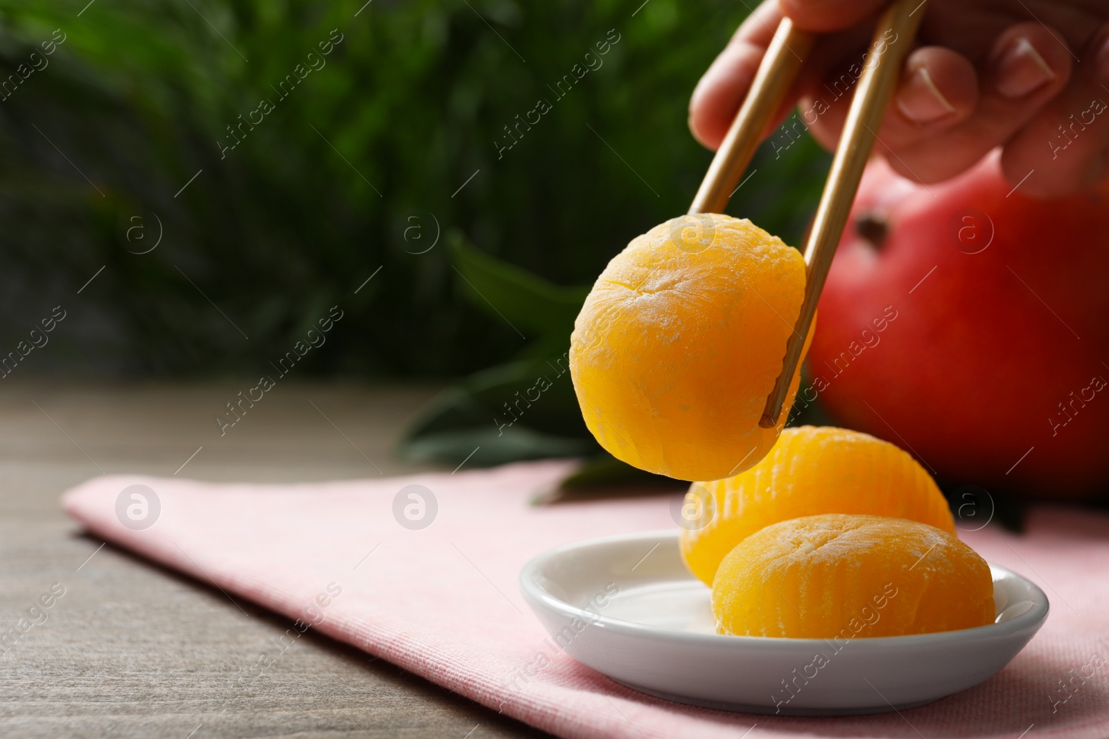 Photo of Woman eating delicious mochi with chopsticks at table, closeup. Space for text