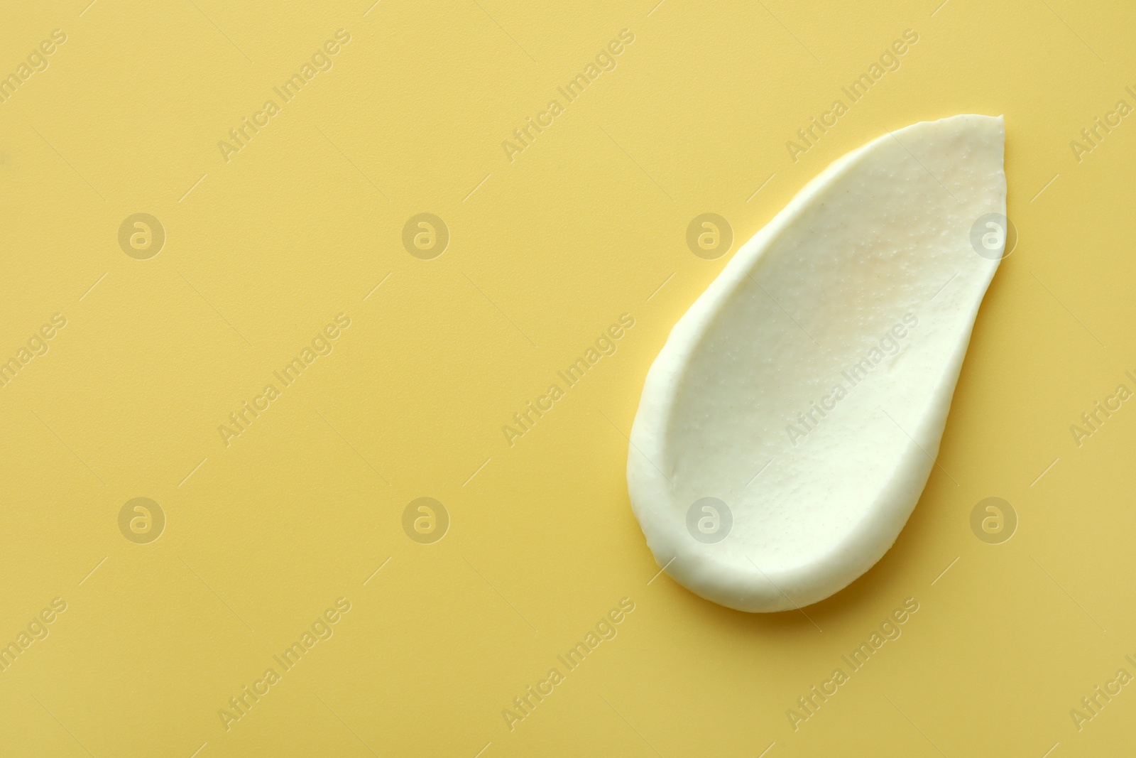 Photo of Sample of face scrub on yellow background, top view. Space for text