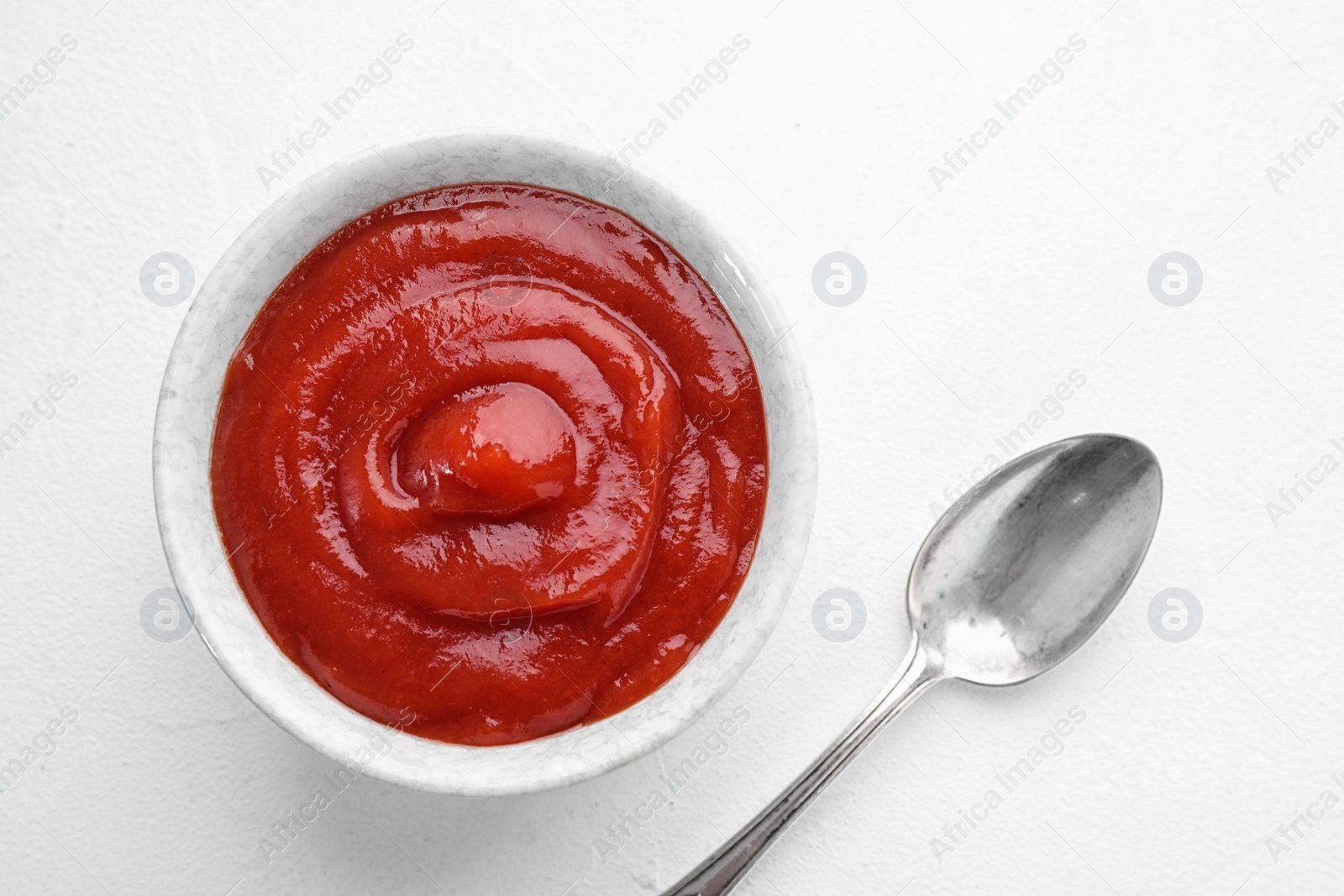 Photo of Tasty tomato sauce and spoon on white table, flat lay