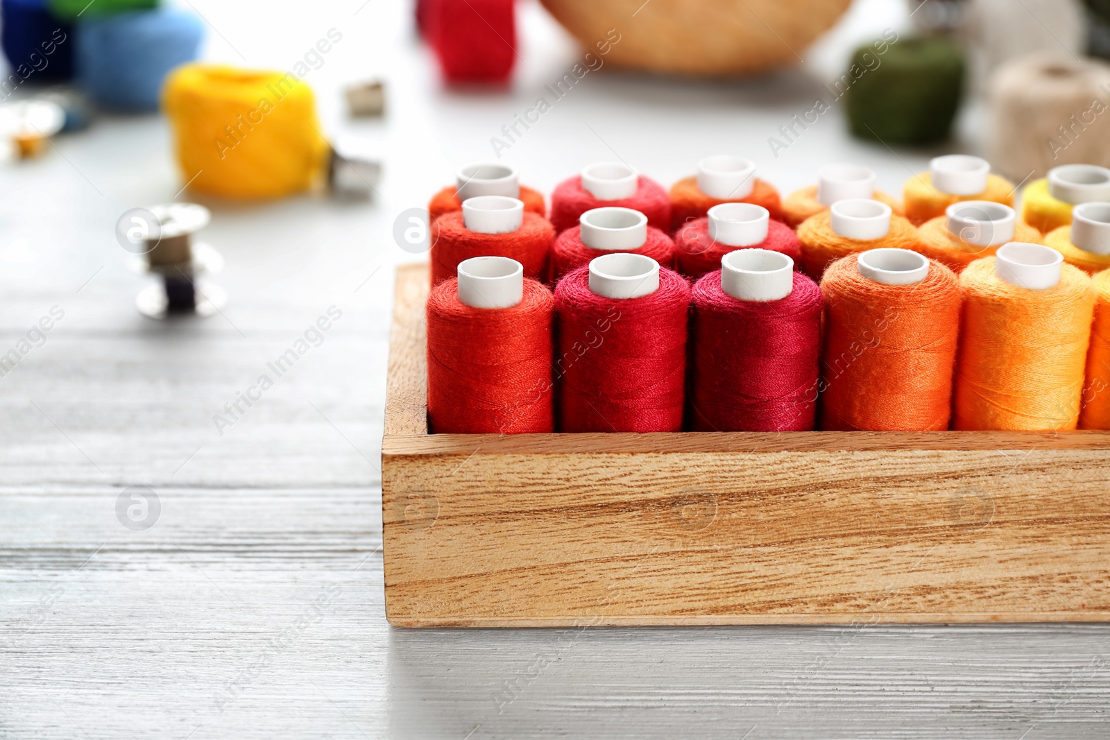 Photo of Container with set of color sewing threads on wooden background