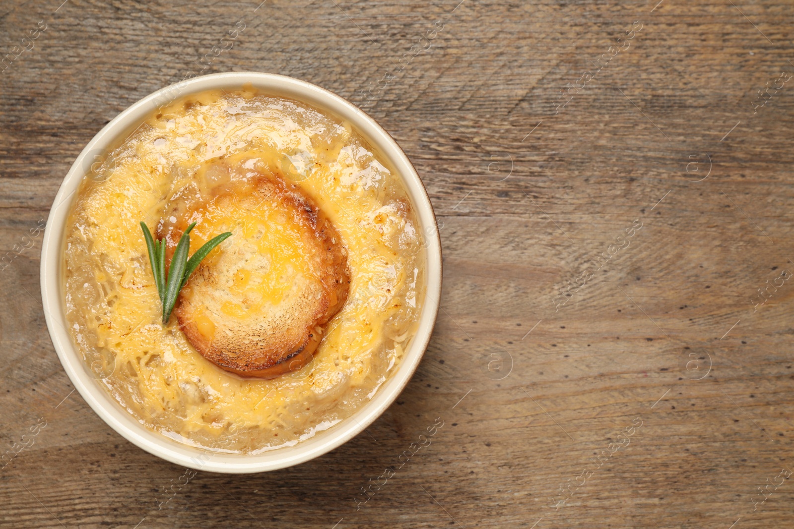 Photo of Tasty homemade french onion soup on wooden table, top view. Space for text