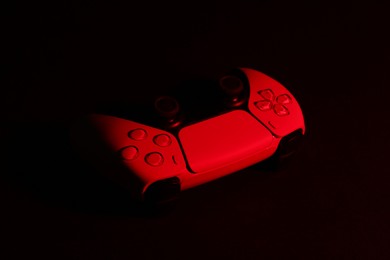 Photo of Two wireless game controllers on black background in neon light