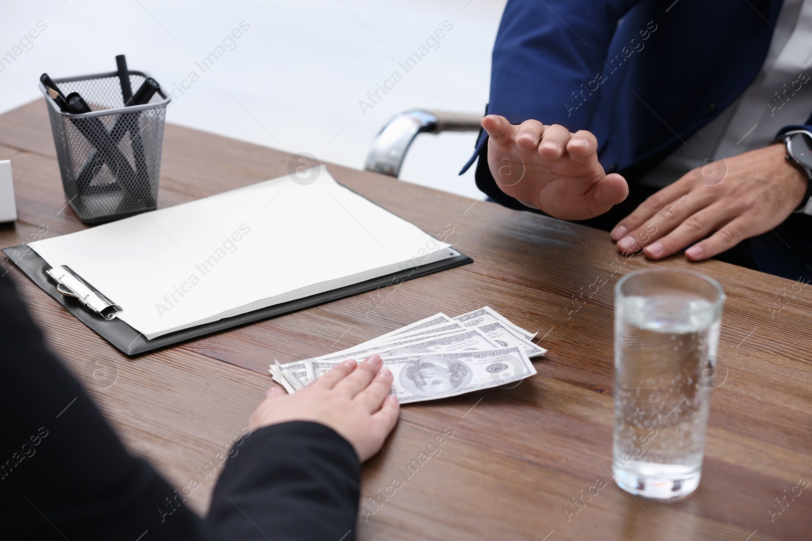 Photo of Businessman refuses to take bribe money at wooden table, closeup