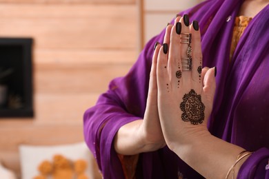 Photo of Woman with henna tattoos on hands indoors, closeup and space for text. Traditional mehndi ornament