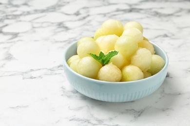 Photo of Plate of melon balls with mint on white marble table