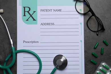 Photo of Medical prescription form, stethoscope, pills and glasses on dark grey table, flat lay