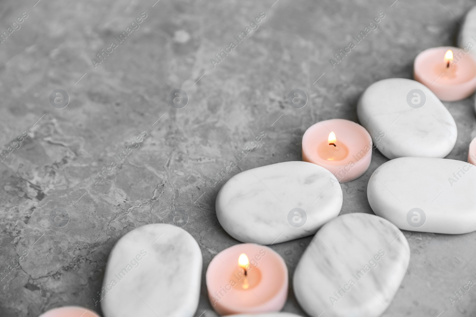 Photo of Composition with spa stones and candles on grey marble background. Space for text