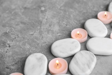 Composition with spa stones and candles on grey marble background. Space for text