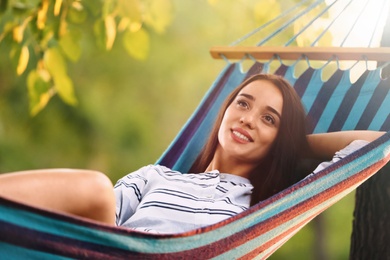 Photo of Young woman resting in comfortable hammock at green garden