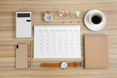 Photo of Flat lay composition with calendar on wooden table