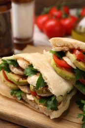 Photo of Delicious pita sandwich with grilled vegetables and parsley on wooden table, closeup